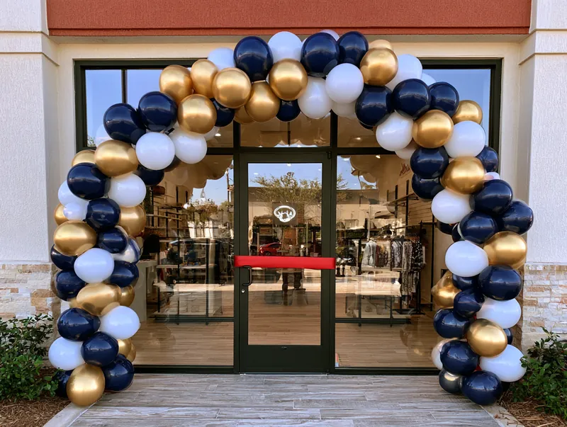Navy and gold balloon arch framing a storefront grand opening in Arlington TX